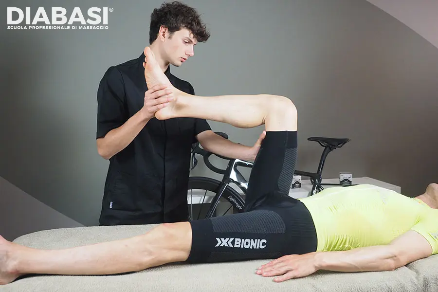 Massaggio Sportivo. Operatore della Scuola professionale di Massaggio Diabasi esegue una manovra di mobilitazione dell'anca e stretching passivo su un atleta ciclista per il recupero muscolare.