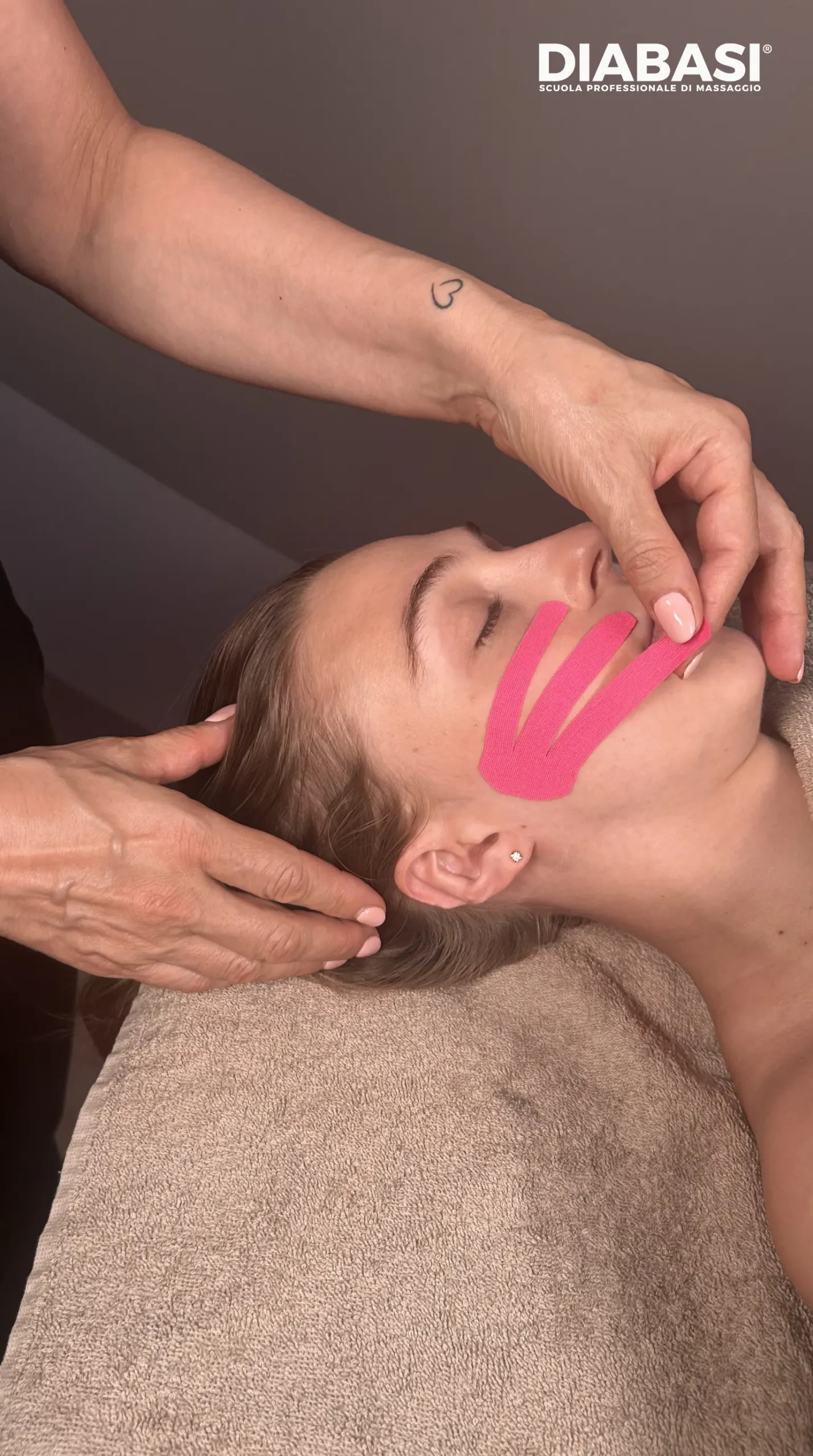 Applicazione di nastro elastico rosa con taglio a ventaglio per il face taping nel massaggio viso lifting.